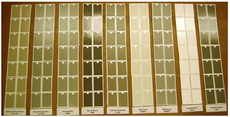 Figure 1. Photo. Composite of small panels. This photo shows the 4-by-6-inch (10-by-15-cm) panels. The panels are placed in 2-column sets, with each column consisting of 7 panels, making a total of 14 panels for each coating system. The individual coating systems are labeled below the columns. Panels are shown for all coating systems except glass flake reinforced polyester. All panels are covered with white tape around the edges and on the top in the center, where they are identified by numbers. 