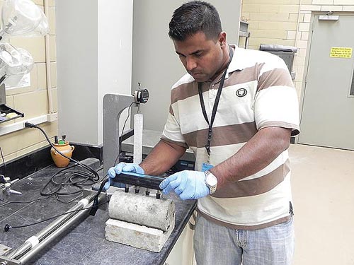 This photo shows a person reading the electrical resistance of a concrete cylinder using a four-point Wenner probe as part of the surface resistivity (SR) test protocol.