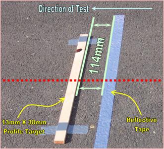 Figure 83. Photo. Section starting stripe and bump target placed on the pavement. This figure shows a reflective tape placed at the start of the section. A wood strip 13 mm by 38 mm is taped to the pavement 114 mm in front of the leave edge of the reflective tape. The 38 mm side of the wood strip is placed perpendicular to the travel direction.