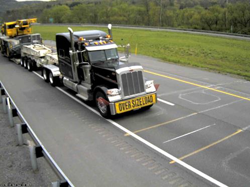 Figure 30. Photo. Eleven-axle Class 13 truck at Pennsylvania site. This photo shows an 11 axle Class 13 truck consisting of a heavy-duty, 3-axle tractor pulling a low-boy trailer with an additional articulated, king pin-equipped three axle low-boy unit acting as a connection between the tractor and the load-carrying trailer in order to further spread the weight of the oversized load as it travels in the right lane of a highway.