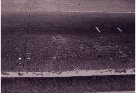 The figure consists of a photograph showing high severity cracking in the travel lane of the test section.