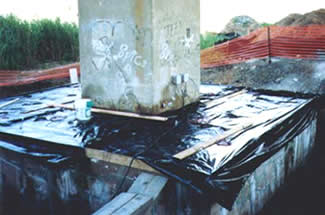 Figure 38. Photo. Application of an Electrochemical Lithium Migration Technique for a Pier Footing on the New Jersey Turnpike. Two devices are fastened to the side of the footing, and the base is covered with a tarp.