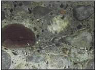 Figure 10. Photo. Example of a Polished Concrete Surface. This photo shows a microscopic view of a polished concrete surface, and the aggregate particles along with small vertical cracking can be seen.