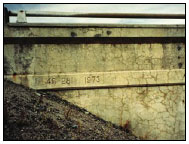 Figure 6. Photo. Surface Discoloration Caused in a Bridge Structure Caused by ASR. This photo shows the side of a bridge structure with extensive horizontal and vertical cracking and surface discoloration.