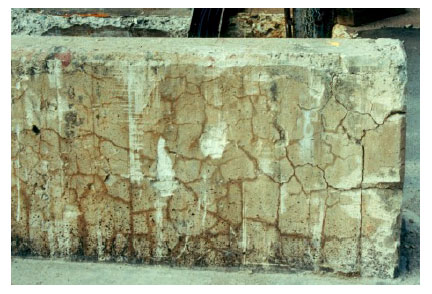 Figure 6. Photo. ASR-Induced Damage in Unrestrained Concrete Element.  Uniform Expansion in All Directions Results in Classic Map-Cracking.  This photo shows a series of interlocking, jagged-shaped cracks on the surface of a concrete barrier.