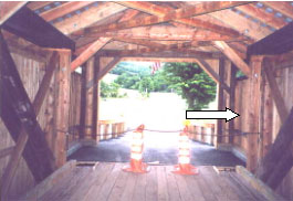 The picture shows the interior of a bridge with a white arrow pointing to the shelter panel that covers but is separate construction from the trusses.