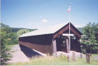 This picture shows the longest span covered bridge (70 or 64 meters (228 or 210 feet) between abutments) that is a double-barrelled roadway with two lanes. It is not clear if the structure between the roadways is a structural truss, but it is likely. The bridge has a flagpole and appears to be closed to vehicles.