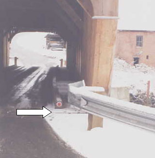 The arrow in the picture points to a reflector that has been installed as a transition from the metal approach railing to the inside curb of the bridge.
