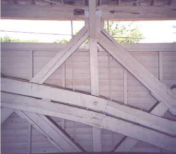 The picture shows the vertical truss post with diagonal supports. Superimposed against this configuration are two segmented arch supports.