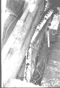Figure 175 Depicts the "rat's nest" of wiring accompanying the installation of the 46 transducers. The equipment is shown mounted on top of the lower bottom chord element. The upper bottom chord element is in the foreground. The edge of the nail-laminated deck is shown along the right edge (a curb timber had been removed). Photo.