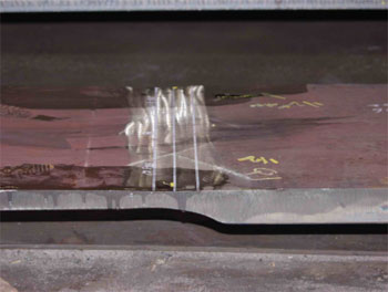 The photo shows a side view of field specimen G5G-TF1-TopF with the weld oriented vertically. The specimen is comprised of a thicker plate to the right and a thinner plate to the left of the photo.