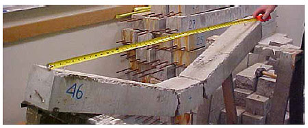 Figure 63. Photo. The damage mode measured for half of the under-reinforced beam specimens is two major cracks beneath the impactor points, without rebar breakage. This is a photo of an under-reinforced post-test beam. It has been removed from the test fixture and is sitting on a saw horse. The damage is two major cracks beneath the impactor points, which separates the beam into three pieces. The pieces are connected via the reinforcement.