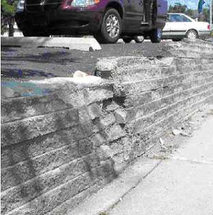 Figure 14. Photo. Effects of drainage and salt exposure from parking lot above SRW. Picture shows a section of wall deterioration from a parking lot above the SRW wall due to drainage and salt exposure.