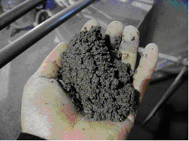 Figure 5. Photo. View of mix during production of SRW units at block plant. Photo of a person's hand holding mix.