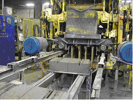 Figure 6. Photo. SRW unit immediately after compaction and demolding. Photo of SRW blocks coming out of large machine at block plant.