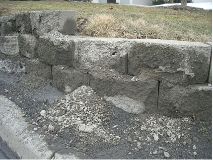 Figure 8. Photo. Condition of SRW in Ithaca, NY. Picture shows a damaged SRW wall where the wall has deteriorated and the concrete is on the ground below the damaged blocks.
