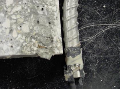 Figure 110. Photo. Top bent bar from specimen MS-BTNB-316-C after removal. This is a photograph of a top bent bar from specimen MS-BTNB-316-C after removal. A small amount of corrosion product staining is apparent on the concrete at the heat shrink sleeve.