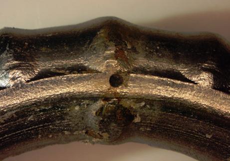 Figure 112. Photo. Corrosion at an intentional clad defect on the top bent bar from specimen MS-CBDB-SMI-B. This is a photograph of corrosion at an intentional clad defect on the top bent bar from specimen MS-CBDB-SMI-B.