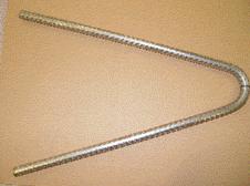 Figure 1. Photo. 2304 SS bar after bending. The photo shows a 0.5-m length of #5 (16-mm-diameter) 2304 SS bar bent into approximately a 30-degree angle. The bar is flat and shown on a horizontal brown surface, and the photo is taken from above. The bar is a shiny metallic material with a lugged surface typical of reinforcing bars for concrete. This is the type of sample used for the stress corrosion cracking test.