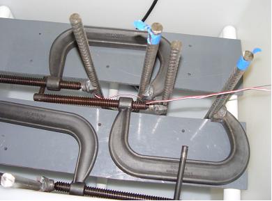Figure 4. Photo. Top view of two specimens with C-clamps in the test tank.