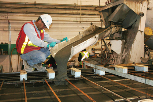 This photo shows ultra-high performance concrete (UHPC) being discharged from a ready-mix truck down a chute into a precast girder form. The UHPC is self-consolidating.