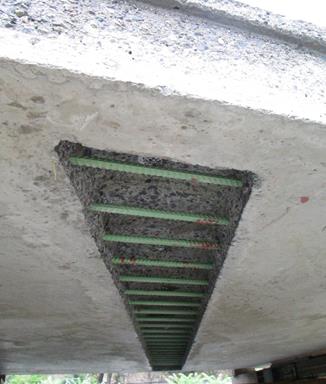 This photo shows the hidden connection on the underside of a precast concrete deck panel. The bottom mat of epoxy-coated reinforcement is visible passing through the void. The void interface has an exposed aggregate finish.