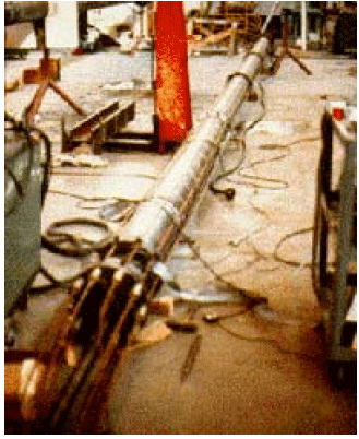 The figure shows a full-scale pipe pile being instrumented in the laboratory prior to field installation for testing in clay. The pipe pile is laid down on the floor with sensors and wires around the perimeter.