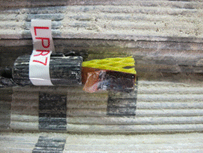 This photo shows a corroded and disfigured linear polarization resistance (LPR) sensor 7. The sensor is located in position between two strands with a large amount of salt and zinc oxide build-up. The electrodes are completely black. 