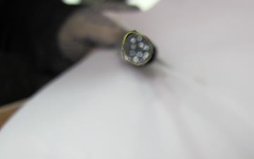 This photo shows an intact coupled multi-electrode corrosion carbon steel sensor (CMAS CS) 2. The head of the sensor is shown with all electrodes clean and showing resistance to corrosion. The electrodes rest in a clean, black matrix. 