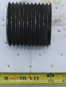 Figure 3. Photo. Received threaded sample after cleaning. This photo shows a completely threaded round piece of metal. A ruler in the foreground shows the threaded portion is approximately 3 inches long. The metal piece appears to have an aspect ratio of approximately one to one, indicating its diameter is also about 3 inches. There appears to be about 10.5 threads.