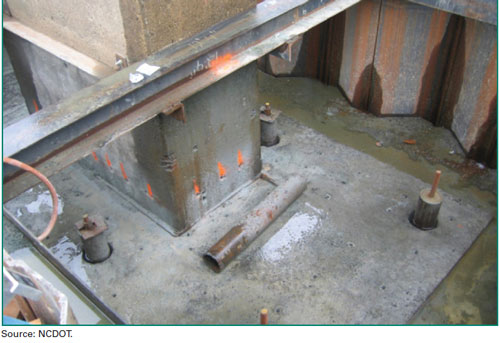 Figure 16. Photo. An existing foundation strengthened with micropiles. The figure is a photo of an existing foundation strengthened by micropiles on the Yadkin River Bridge 91 in North Carolina. The photo shows the foundation top (pier cap) containing four micropiles. Each micropile is shown to be centrally reinforced with a single bar.
