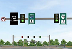 Off-peak upstream signalized intersection (DRLT). This image shows three guide signs above a signalized intersection mounted on a cantilever structure. On the far-left lane, there is a no left turn arrow, as well as a changeable guidance sign that reads “THIS LANE CLOSED” in white text on a black background. The middle lane has a static sign that reads “South 495” with an arrow pointing straight through the intersection. The far-right lane has a static sign reading “West 193” with an arrow pointing straight through the intersection. There are also two three-lensed vertical signal heads located on the cantilever structure; one signal head is located between the left and middle lane, while the other is located between the middle and right lane.