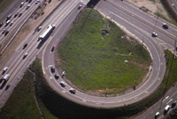 This photograph is an aerial shot of an exit ramp that connects one road to another. The exit ramp curves around, forming one quarter of what could be a cloverleaf interchange.