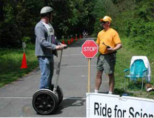 Figure 51: Photo. A Segway user on the Paint Branch Trail in Maryland. A participant standing on a Segway is talking to an event staff person.