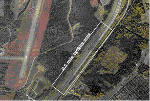 Figure 26.  Photograph.  Test section 8.  An aerial photograph illustrates the location of test section 8 on the Glenn Highway State Route 1 outside Anchorage, AK.  The testing area is located on a straight section of the highway.  The highway begins to curve to the left immediately beyond the end of the test section at the top of the photograph.  The test section is approximately 0.5 mi long.