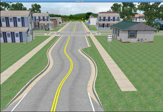 Curb and gutter chicanes condition. The figure depicts a simulator screen capture of the curb and gutter chicanes town condition. It shows a daytime view of a main two-lane undivided roadway running down the center of a small town. The town consists of small homes and stores lining the main roadway. A standard intersection is visible in the foreground, and a second intersection is barely visible in the background. All roadways in the town have curbs, gutters, and sidewalks. They also have double yellow centerlines which are interrupted at the intersections. The minor intersecting roadway running horizontally across the screen has marked crosswalks and stop bars on either side. Marked parking spaces are visible on either side of the main roadway, but no motor vehicles are parked in these spaces. The main difference of this simulated condition from the baseline condition is that a curb and gutter chicane is clearly visible at the entrance to the town. The chicane consists of a compound curve which produces a series of temporary lateral lane shifts before entering the town. The second chicane at the exit from the town is not visible.