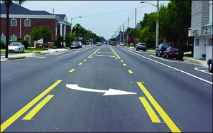 Figure 2. Photo. Three-lane configuration after road diet. (Source: Pedestrian Bike Information Center, Road Diets training module, 2009). This picture shows the same roadway that appears in figure 1 after the road has been reconfigured. The roadway has only one through lane in each direction, a two-way left-turn lane (TWLTL) in the center, and bike lanes and parking on each side of the road.