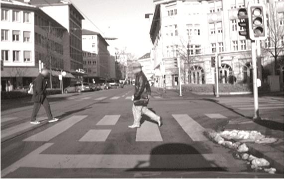This photo shows pedestrians crossing the street at a signalized crosswalk in an urban environment during the day.