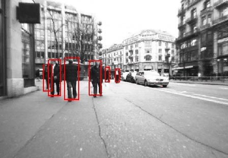 This photo shows pedestrians walking on a sidewalk in an urban environment 98.4 ft (30 m) ahead of a vehicle. They are detected by the appearance classifier by red bounding boxes.