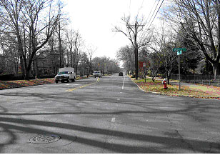 Figure 23. Photograph.  Street view of bicycle example 2. This is one of three photographs of the same intersection. This picture, from the street level, shows a three-leg, signalized intersection of two roads. The main approach road is a two-lane road with a separate left-turn lane approaching the intersection. The secondary street that Ts into the main road is a two-lane road.