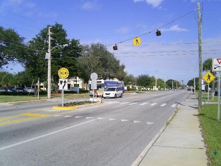 Figure 4. Photo. Northbound view of standard overhead beacon system and crosswalk at 58th Street N with advance yield markings. Click here for more detail.