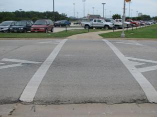 This photograph shows a roadside view of two transverse lines at a raised crosswalk. The lines are two white horizontal strips.