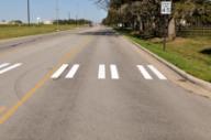 This photo shows an example of the bar pairs markings installed at the study site on F&B Road. Each bar pair consists of two 8-inch strips of parallel white longitudinal markings separated by 8-inch spacing. The strips are 10 ft long. The bar pairs are located on the edge and in the middle of the travel lanes.