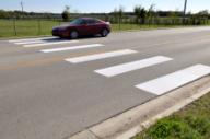 This photo shows an example of the continental markings installed at the study site on F&B Road. Each strip is a white longitudinal marking that is 24 inches wide and 10 ft long. The strips are located on the edge and in the middle of the travel lanes.