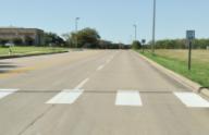 This photo shows the continental markings installed at the study site on Discovery Drive. Each strip is a white longitudinal marking that is 24 inches wide and 10 ft long. The strips are located on the edge and in the middle of the travel lanes.