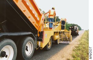 Workers applying a chip seal  treatment on roadway