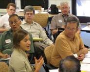 Photo of adults listening to a woman speaking while in a classroom setting