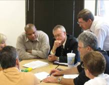 Photo of business people gathered around a table having a meeting.