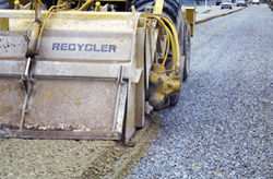 Photo of construction truck laying materials on a new roadway. 