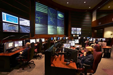 GDOT's Traffic Management Center Operations Floor, with computer workstations for staff and a wall of screens for viewing data and live images of traffic and roadway conditions.